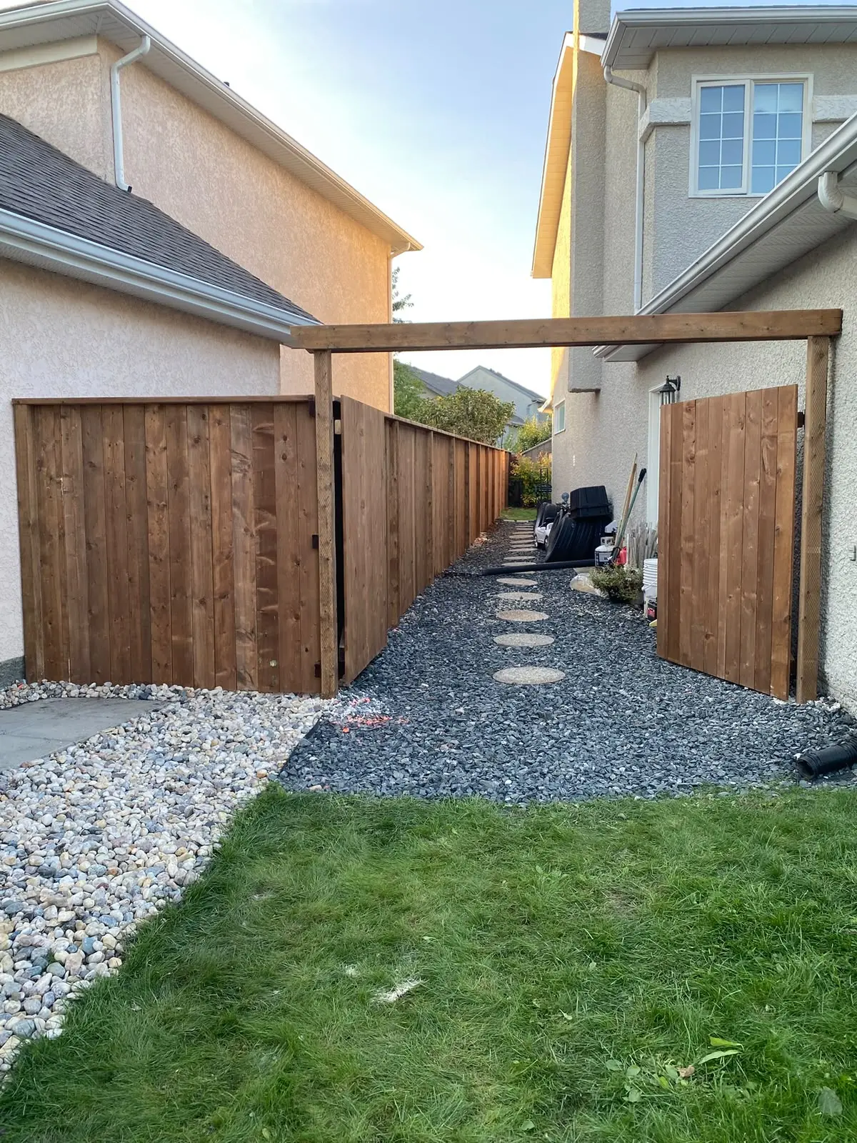 Side-yard wood fence with a wide double gate and an overhead beam