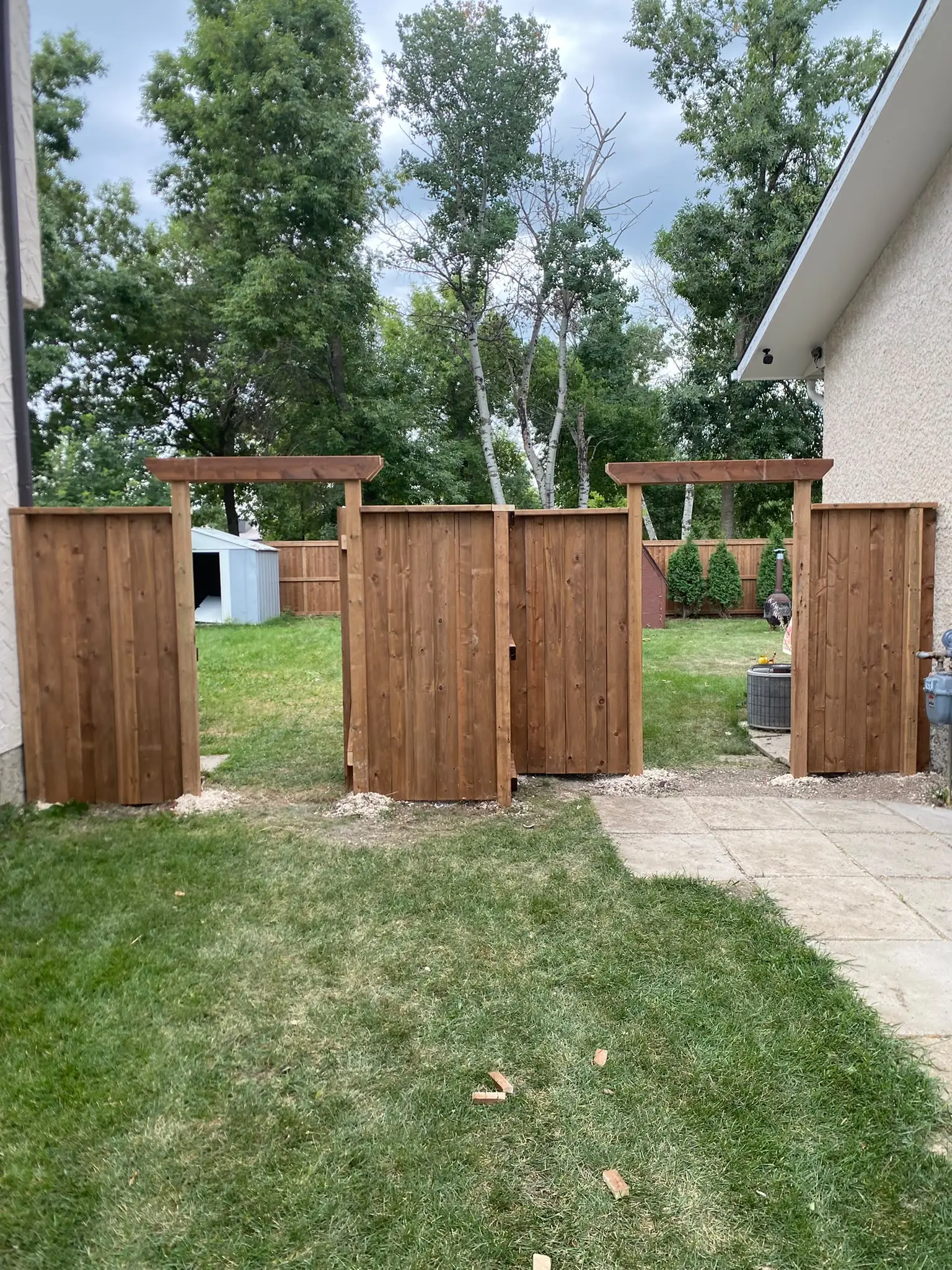 Two wood gates with pergola-style tops between two houses